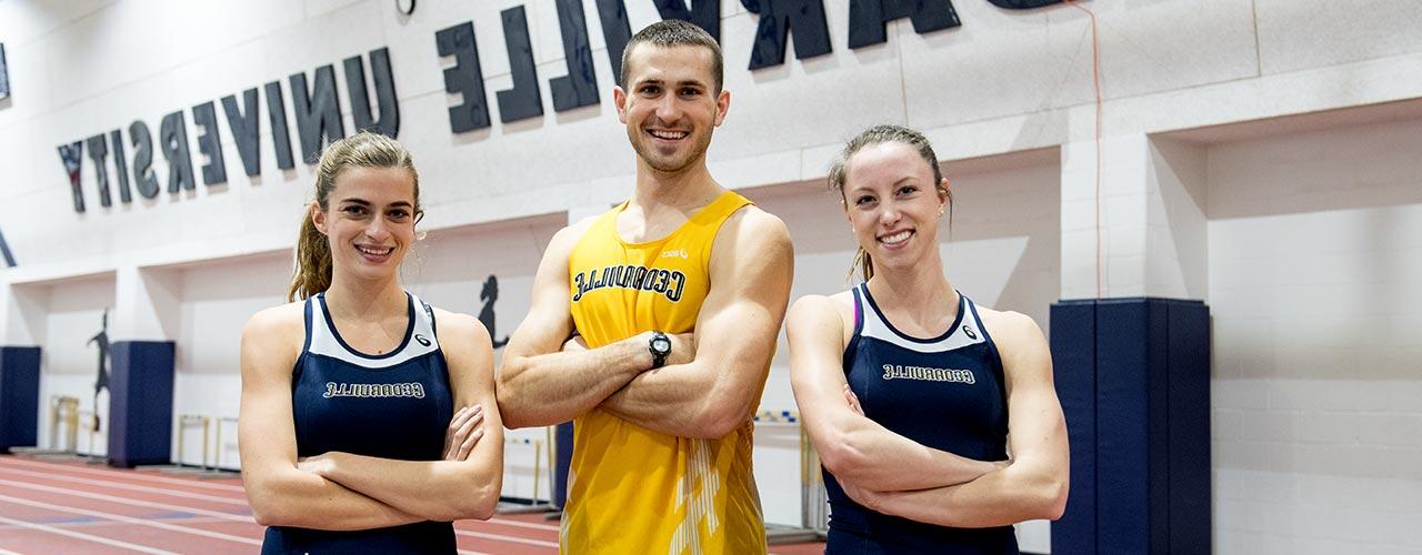 Three track and field athletes sport Jacket’s gear in Doden Field House